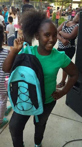 a young girl with a backpack standing on a sidewalk