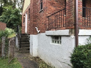 A white building with a red brick chimney and a metal railing.