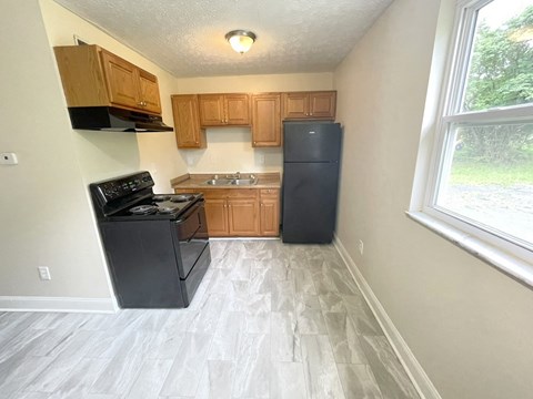 an empty kitchen with wood cabinets and a black refrigerator
