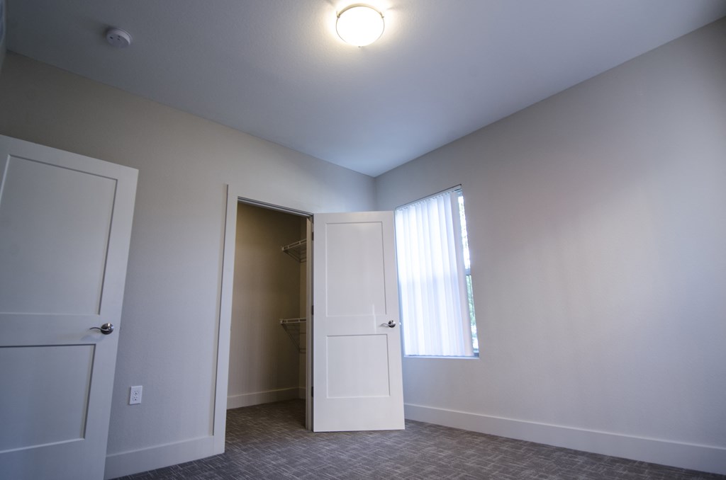 an empty room with a door to a closet and a window