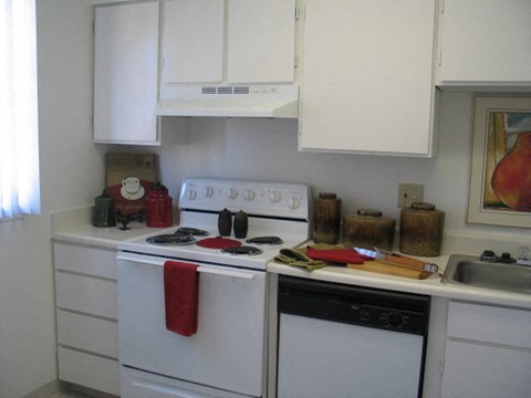 A white kitchen with a red towel on the stove.