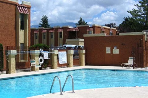 A pool surrounded by a fence and chairs.