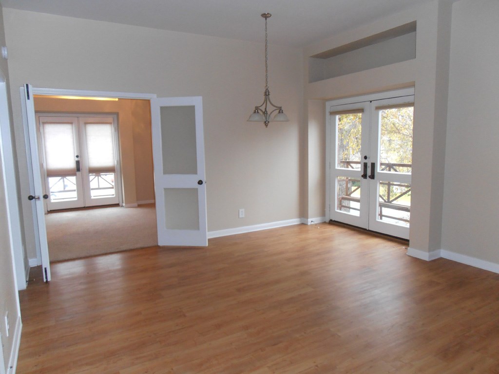an empty living room with a hard wood floor and white doors