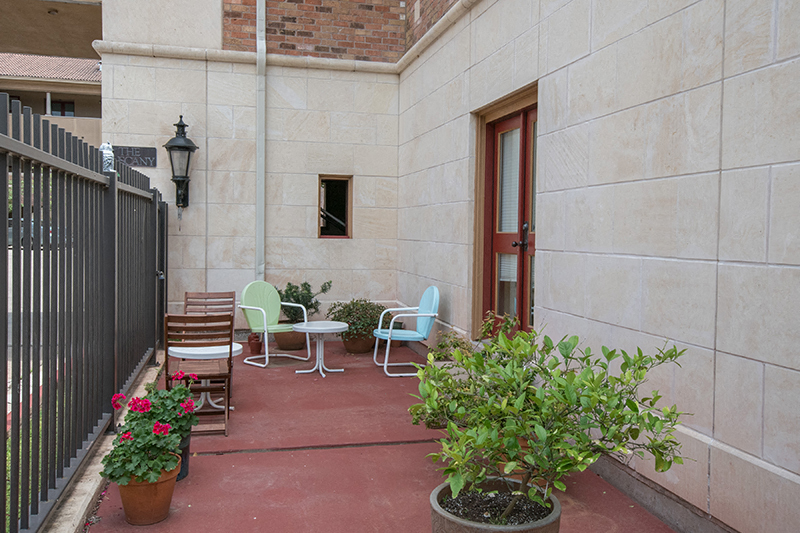 a patio with chairs and plants outside of a building