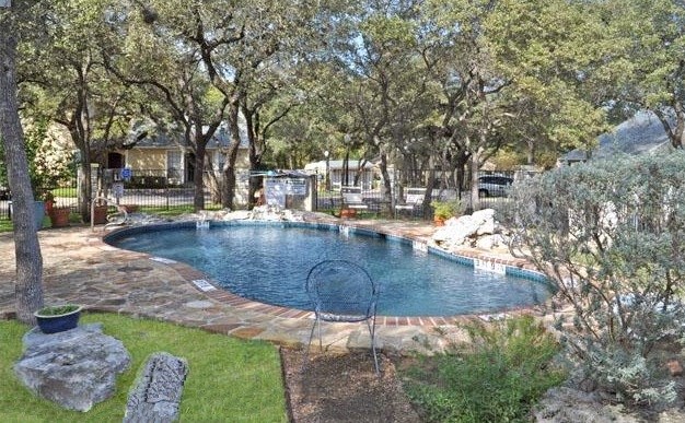 a swimming pool with trees and a house in the background