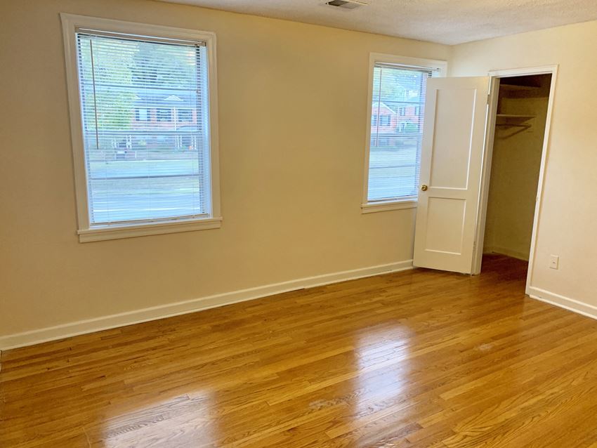 an empty room with a hard wood floor and two windows