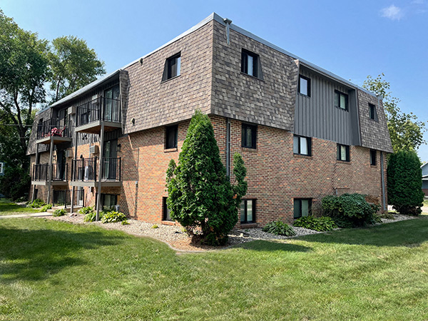 a brick apartment building with a tree in the yard