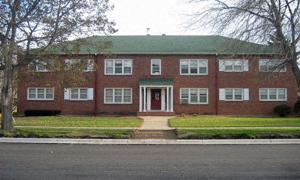 a red brick house with a green roof