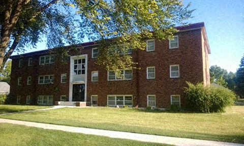 a red brick building with a lawn in front of it