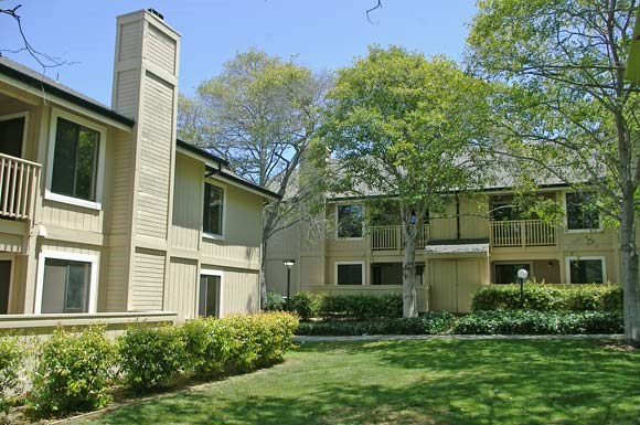 an apartment building with a lawn and trees