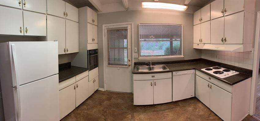 a kitchen with white cabinets and a sink and a window
