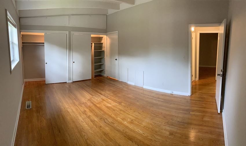 an empty living room with wood floors and white walls