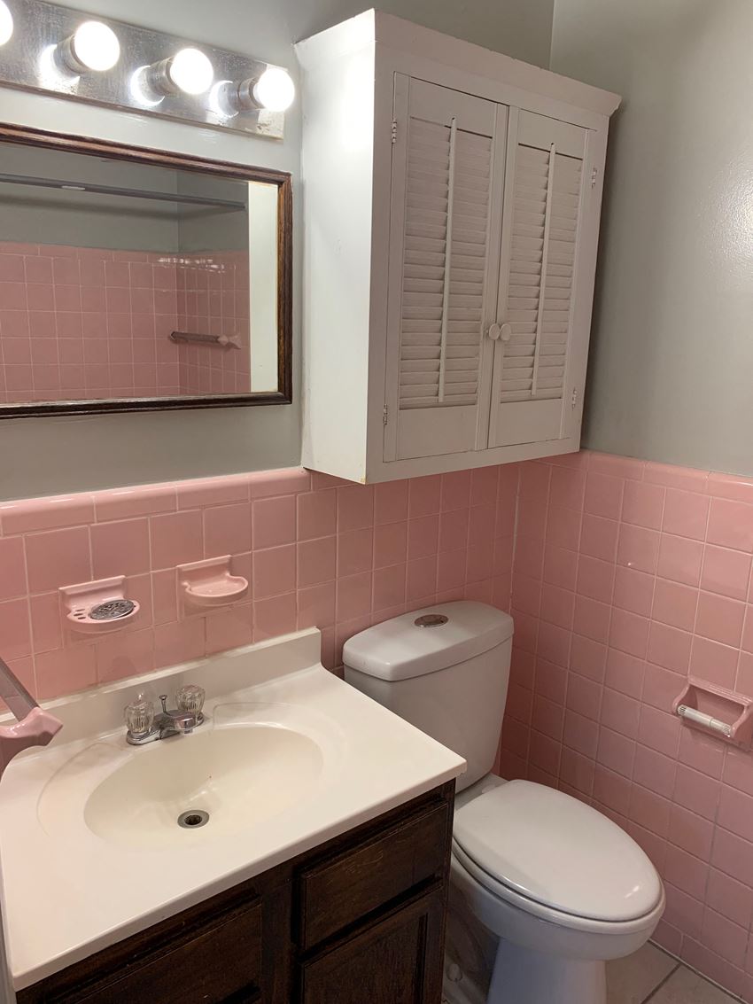 a pink bathroom with a sink toilet and mirror