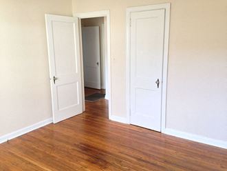 an empty room with three doors and a wood floor