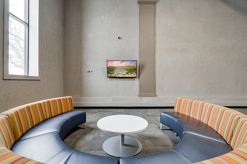 circular couch facing TV on a wall