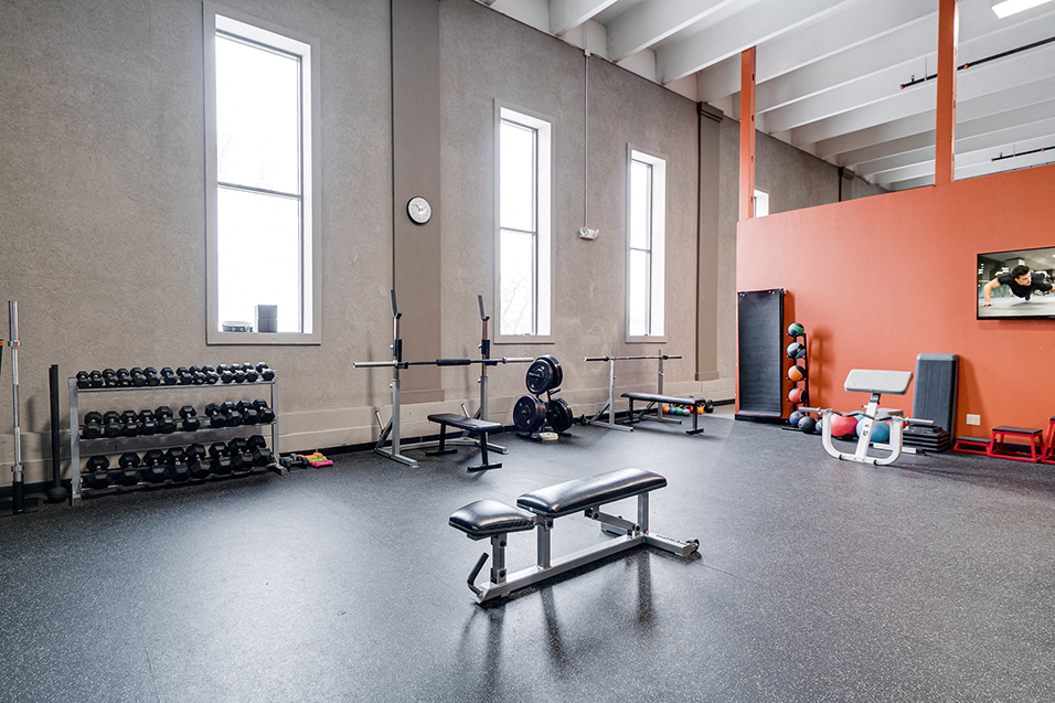 corner of fitness room with bench press and a weight rack