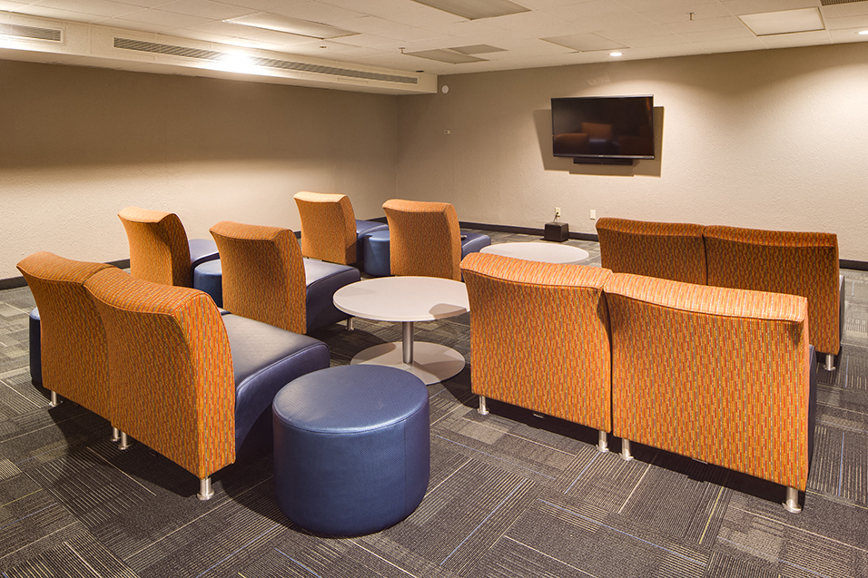 media room with three rows of orange chairs looking towards TV mounted on the wall