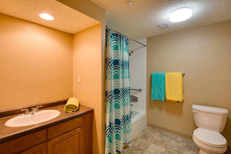 full bathroom with multicolored towels and blue shower curtain