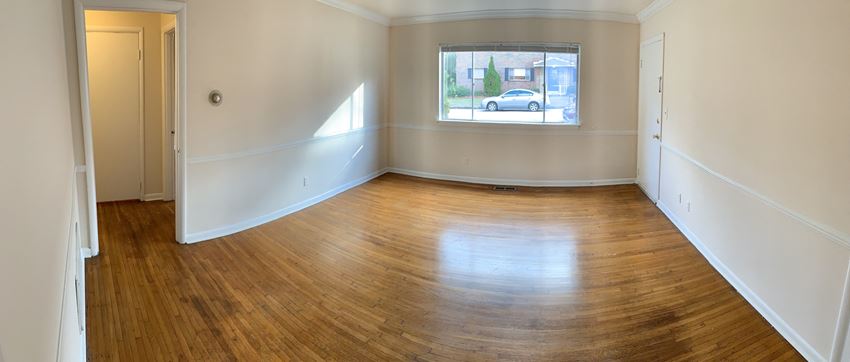 an empty living room with wooden floors and a window