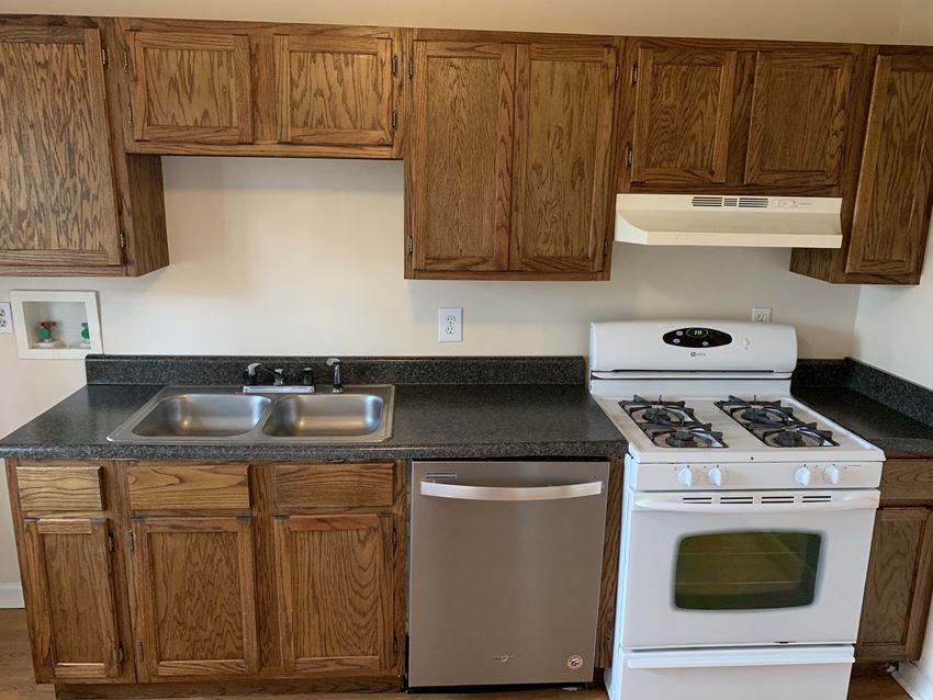 an empty kitchen with white appliances and wooden cabinets