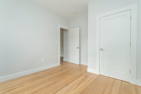 an empty room with a wood floor and white doors