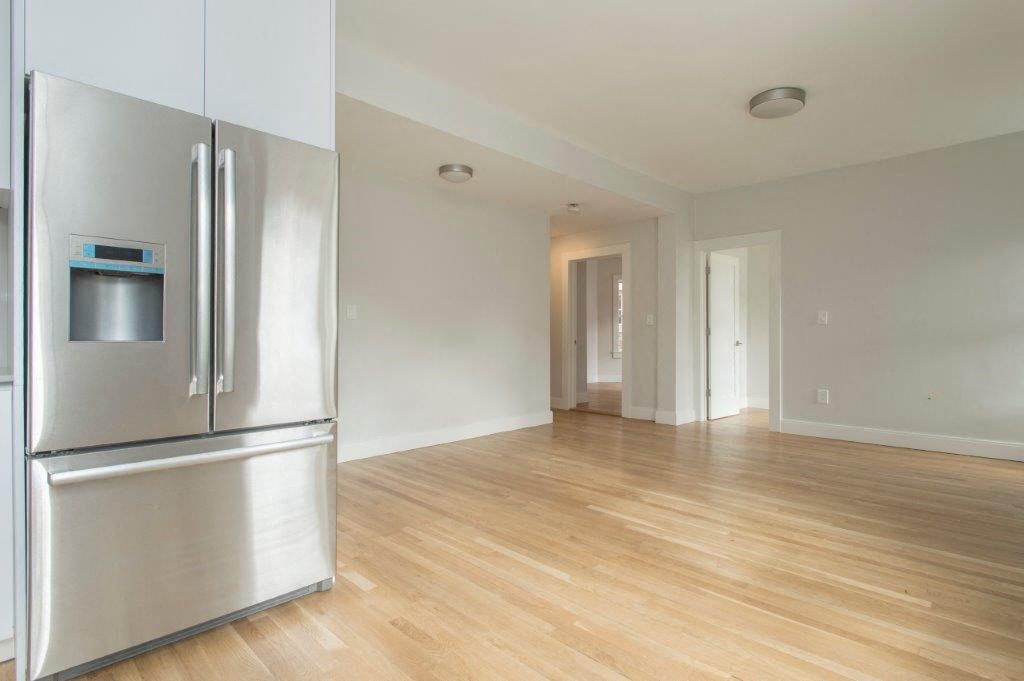 an empty living room with a stainless steel refrigerator