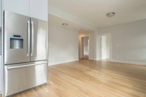 an empty living room with a stainless steel refrigerator