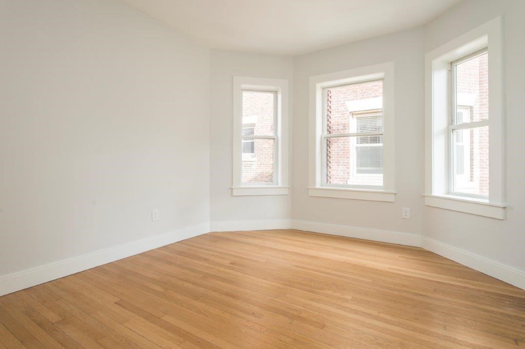 an empty room with a wooden floor and three windows