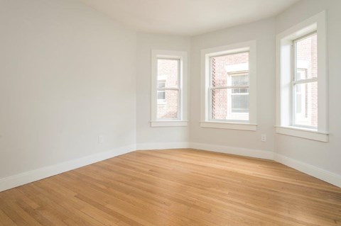 an empty room with a wooden floor and three windows