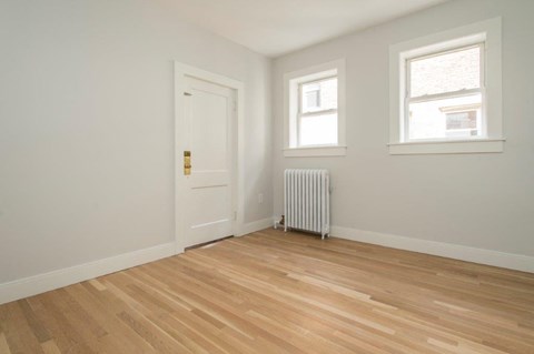 a room with a wood floor and a radiator and a door