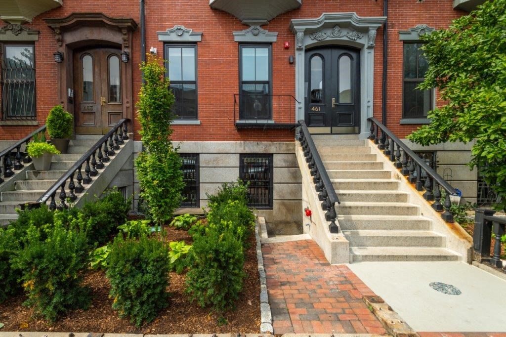 a red brick house with stairs and a garden in front of it