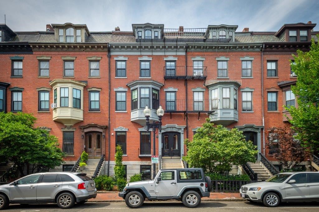 a brick apartment building with cars parked in front of it
