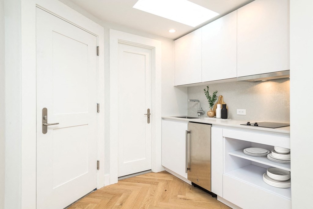 a small kitchen with white cabinets and a wood floor