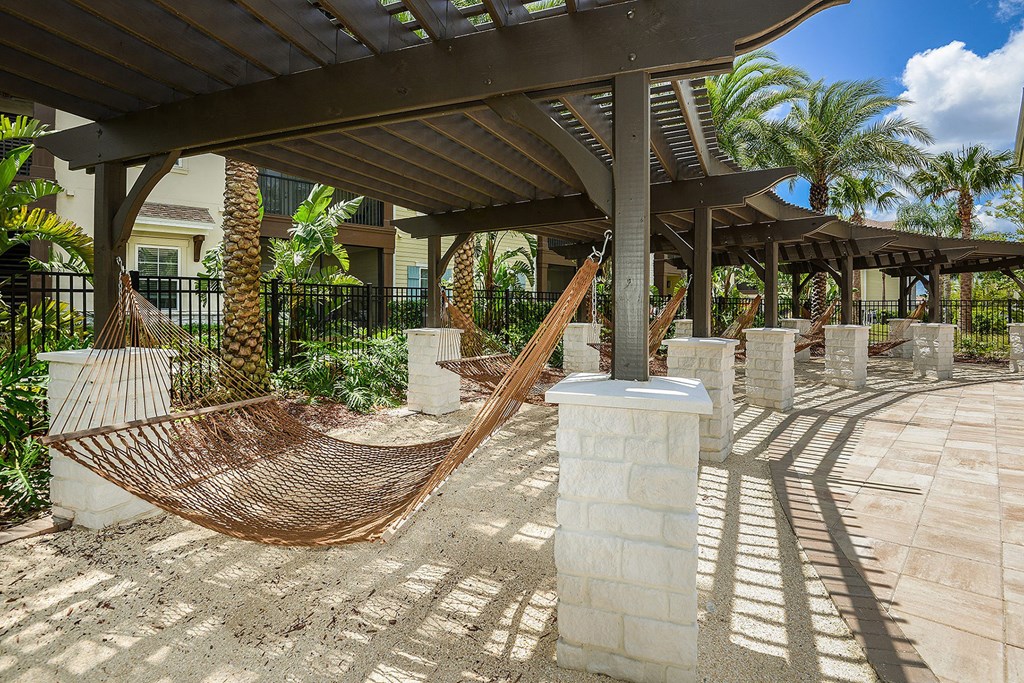 A hammock is strung between two wooden posts in a sunny outdoor area at Cabana Club Apartments, Jacksonville