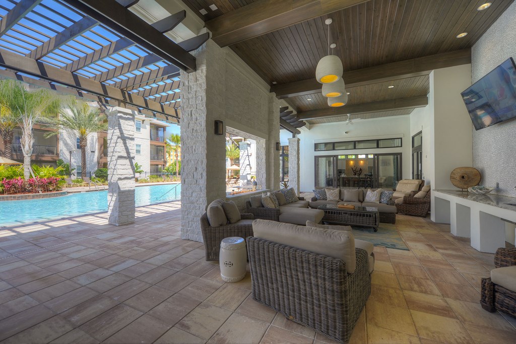 A large, open-air living room with a pool and a wooden ceiling at Cabana Club Apartments, Jacksonville, FL