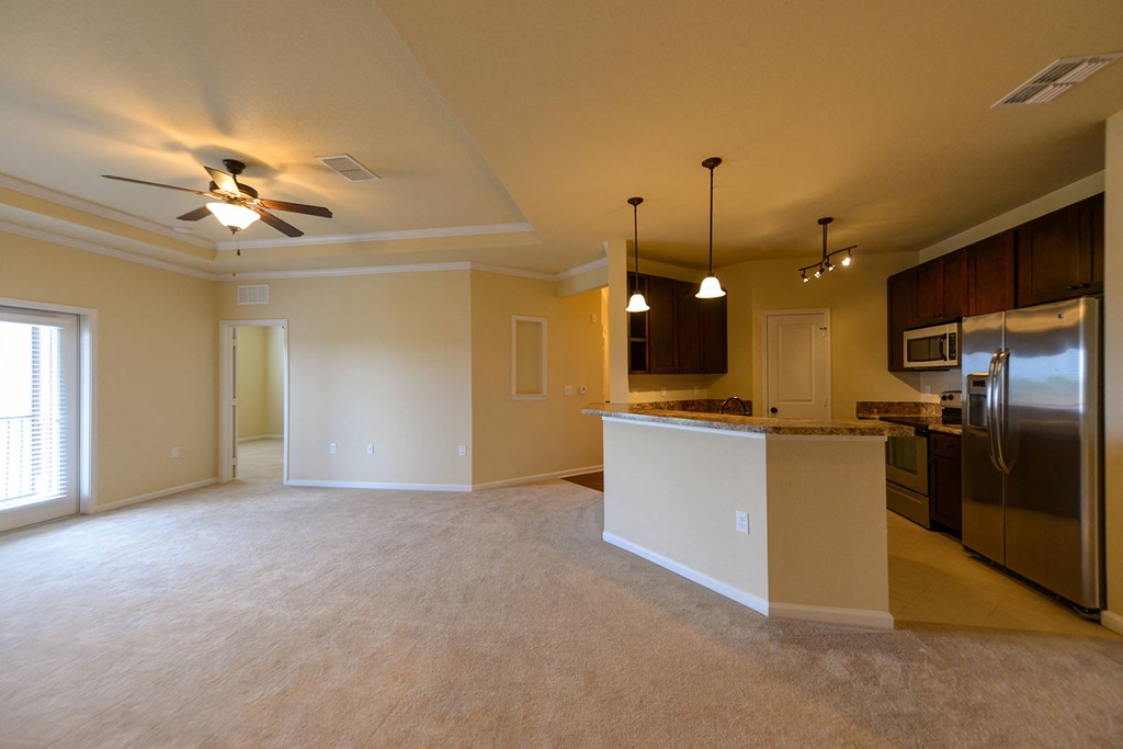 Empty room with a kitchen area in the background at Cabana Club Apartments, Jacksonville, FL