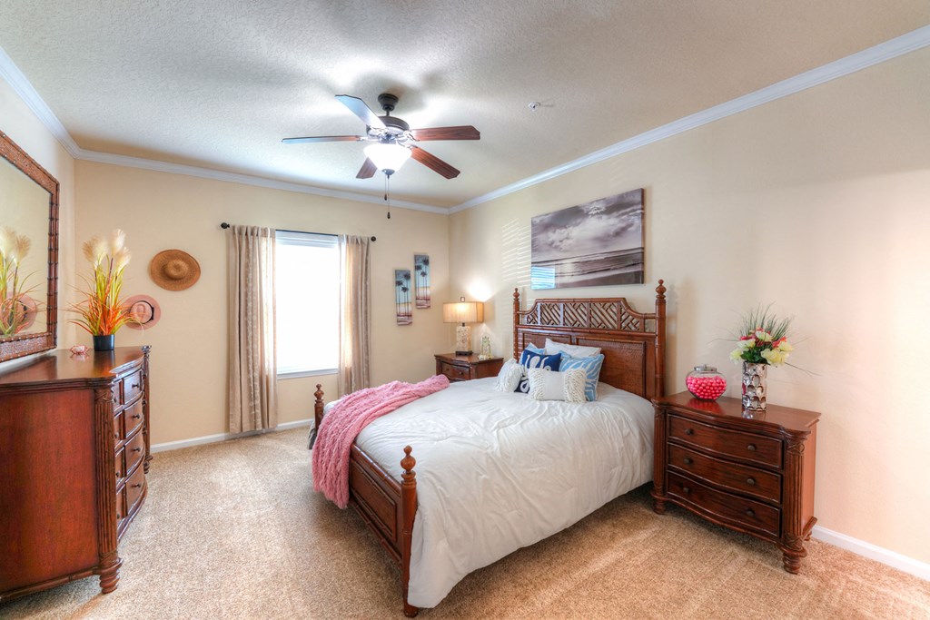 A bedroom with a bed, dresser, and ceiling fan at Cabana Club Apartments, Jacksonville, Florida