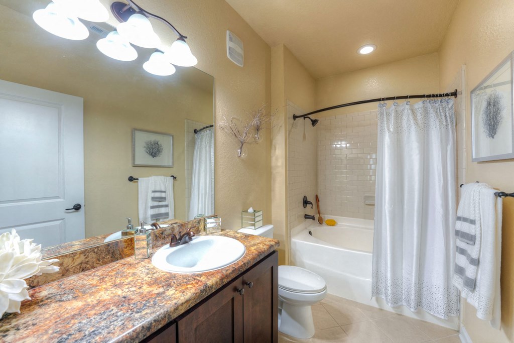 A bathroom with a marble countertop and a white toilet at Cabana Club Apartments, Jacksonville