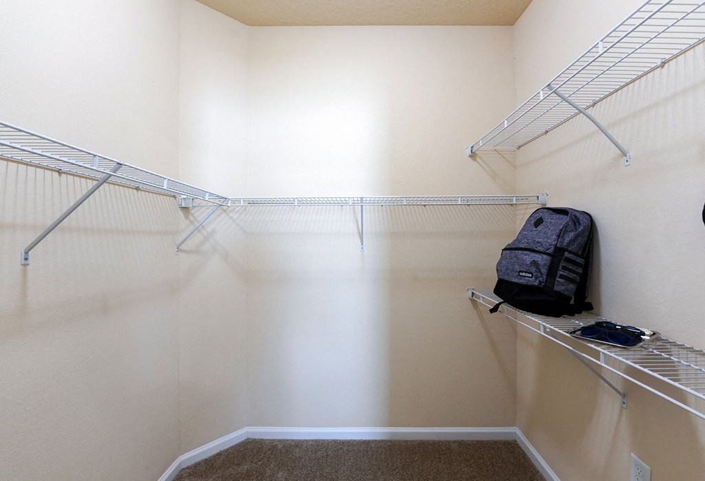 A small closet with a brown carpet and a black bag on the shelf at Cabana Club Apartments, Florida 32256