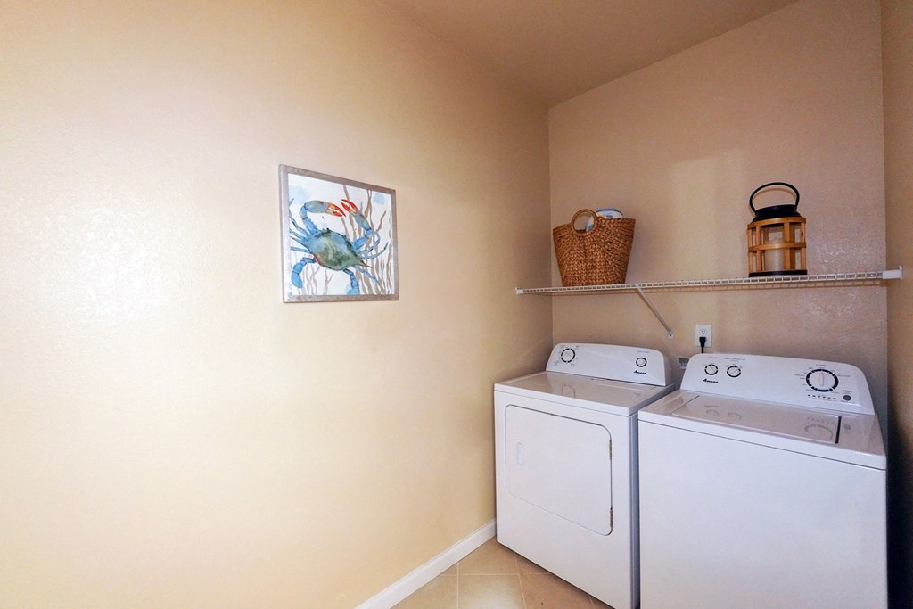 A laundry room with two washing machines and a basket on the shelf at Cabana Club Apartments, Jacksonville, FL, 32256