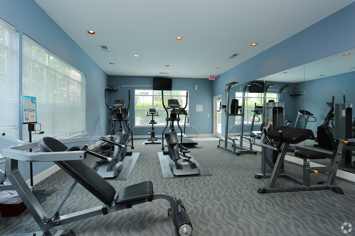 a gym with cardio machines and weights in a building with large windows