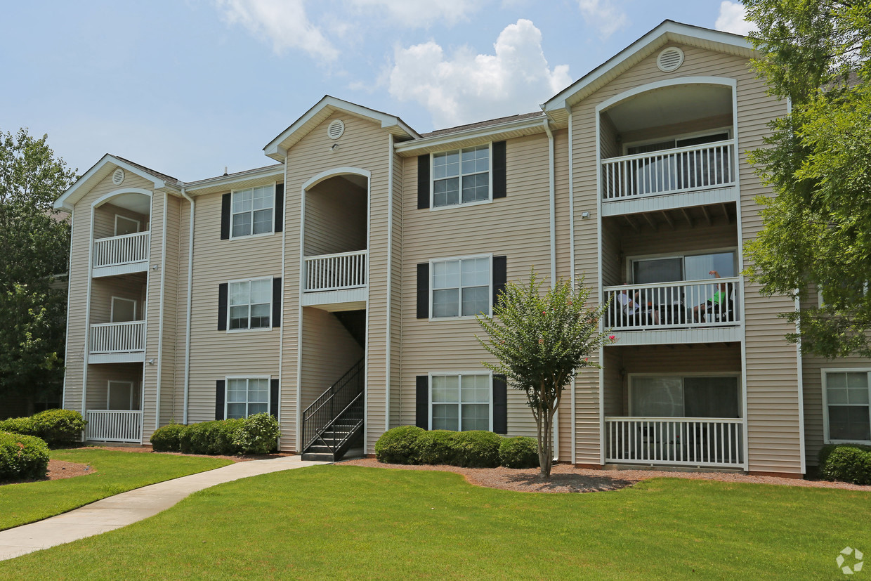 an exterior view of an apartment building with green grass and trees