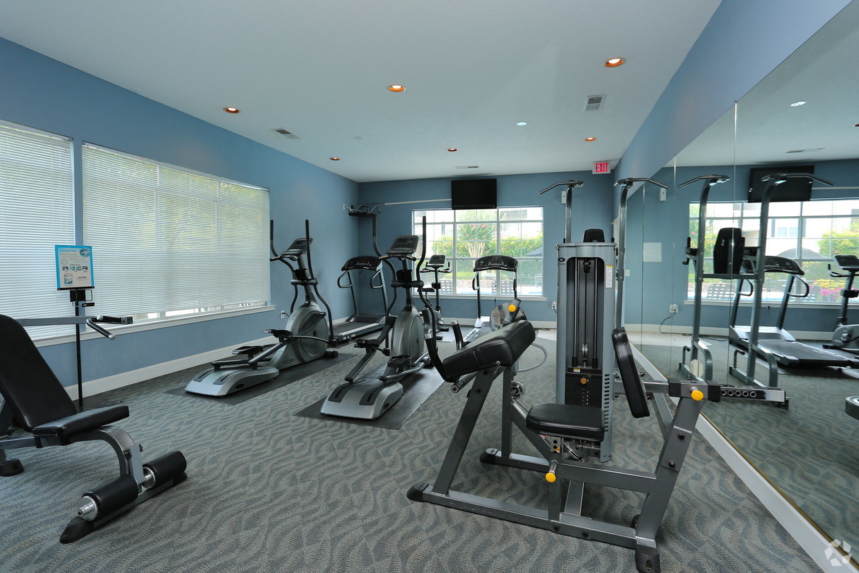 a gym with cardio machines and other exercise equipment in a building with large windows