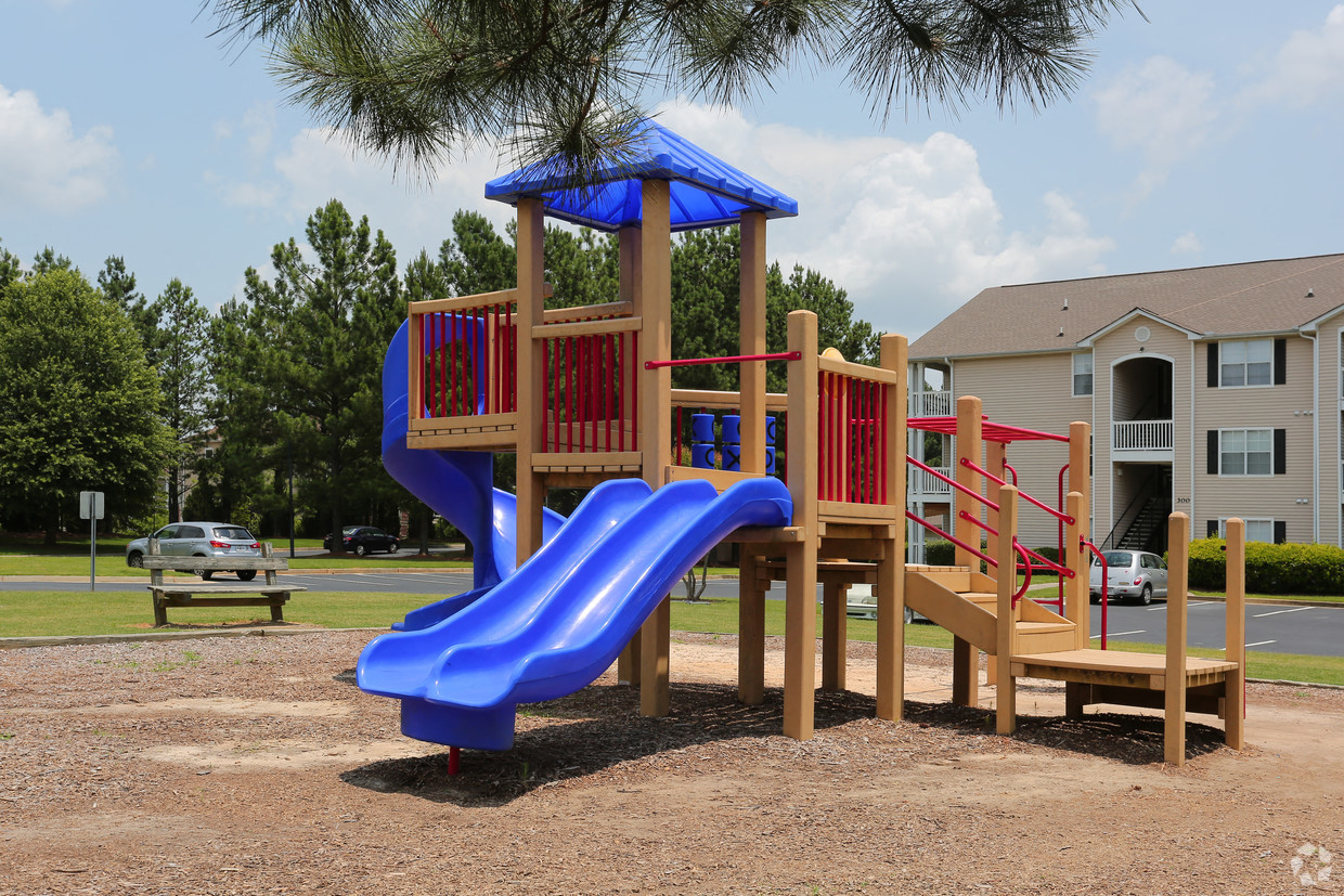 a playground with a wooden playset with a blue slide