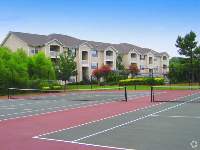 a tennis court in front of an apartment building