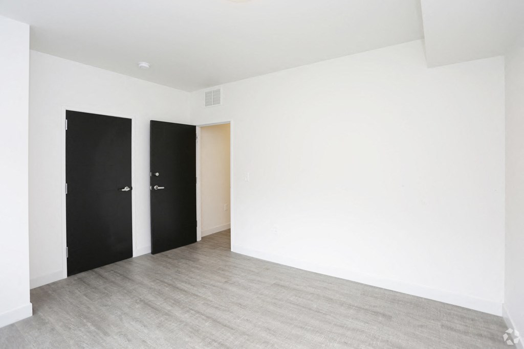 an empty room with white walls and black doors