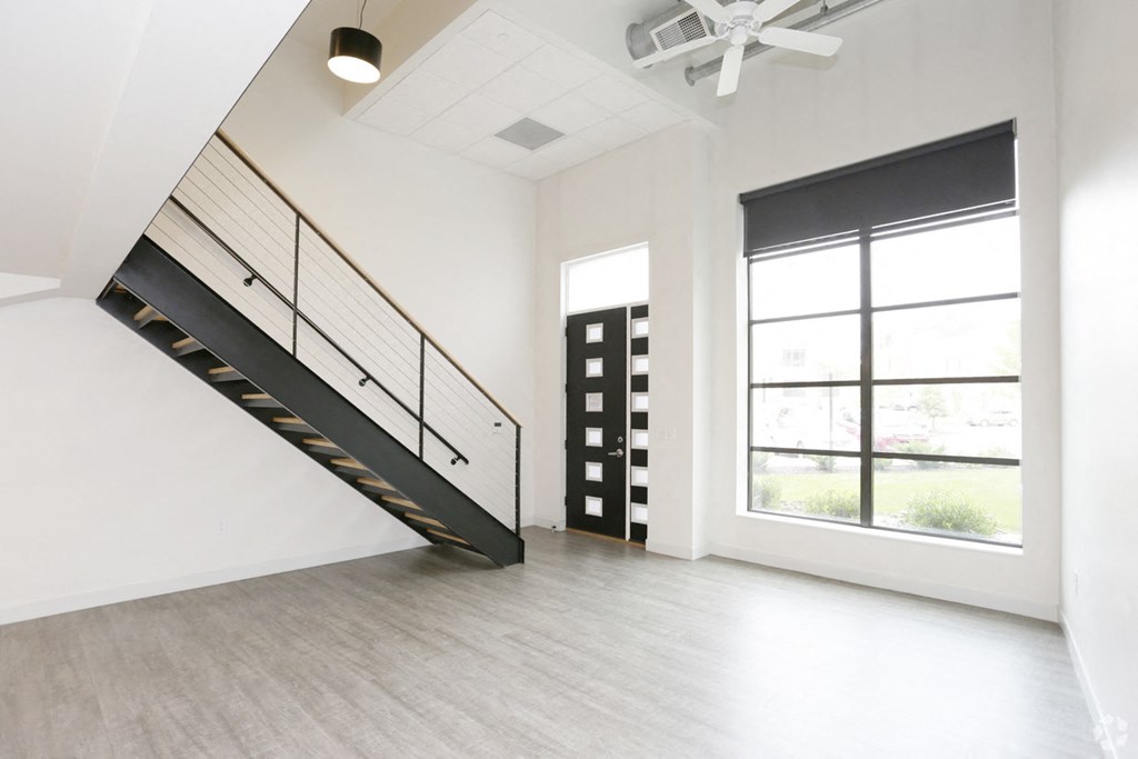 an empty living room with a staircase and a large window