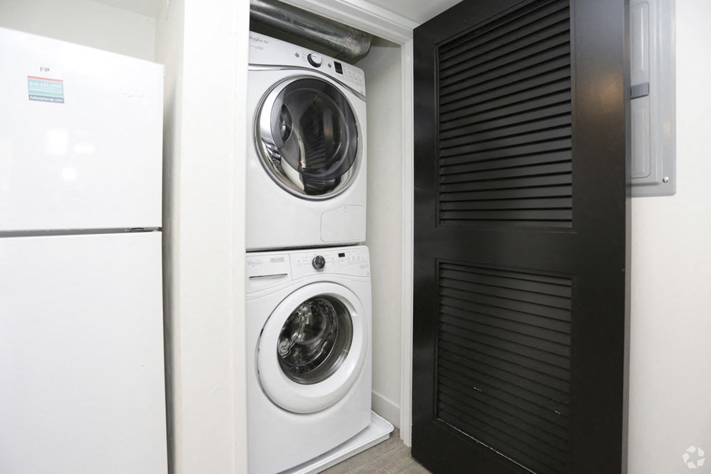 a washer and dryer in a laundry room with a black door