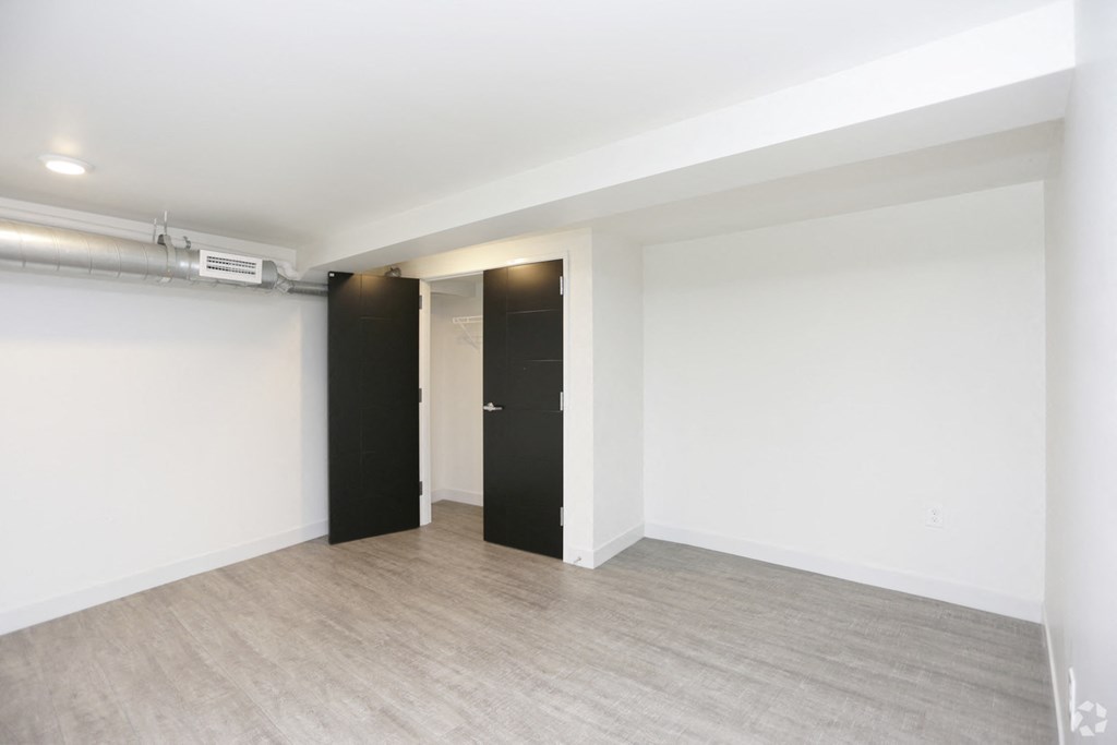 an empty room with white walls and two black doors