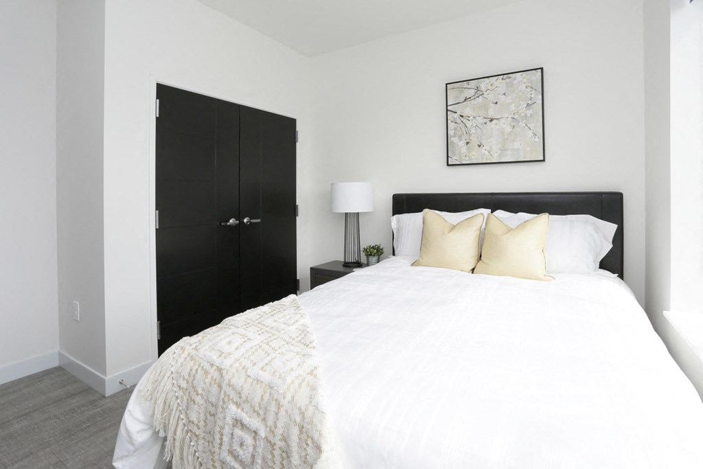 a bedroom with a white bed and a black wardrobe
